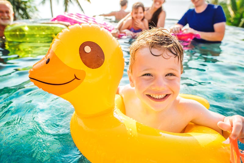 A boy palying in the pool with his family