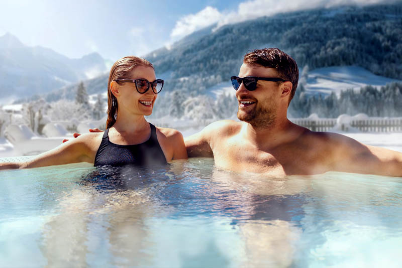 Image of a couple relaxing in an outdorr hot tub in a wintry landscape.
