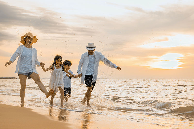 Image of a family playing on a beach at sunset.