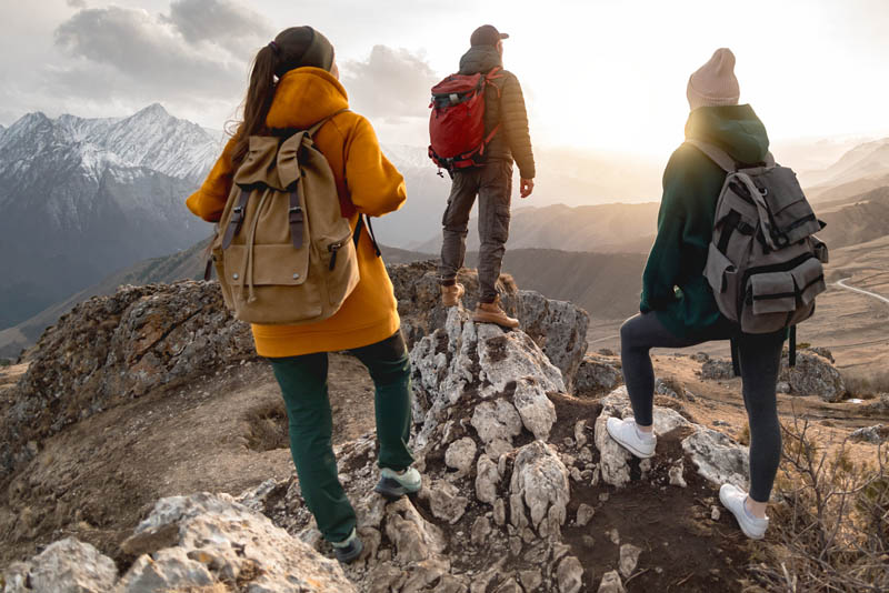 Image of a group of people trekking to a mountian peak and admiring the view.