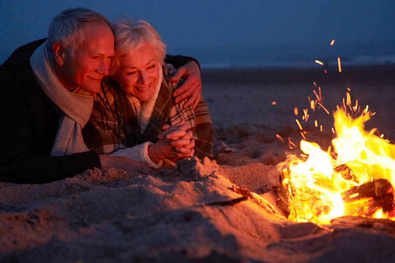 A senior couple relaxing near a camp fire.