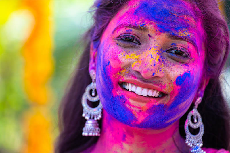 Image of a woman covered in coloured powder at a festival.