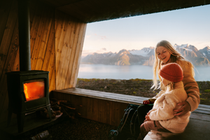 A family relaxing by a log stove in a cosy ski lodge.