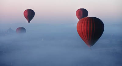 Hot air balloons rising through cloud.