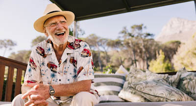 A mature traveller sitting on a veranda, smiling.