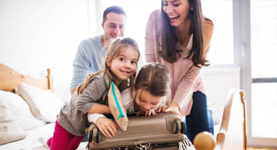 Sisters trying to close packed suitcase.