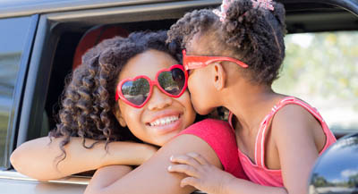 Sisters leaning from car window, smiling.