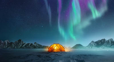 A cosy tent underneath the Northern Lights.