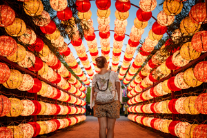 A traveller waliking through an arch of lanterns.