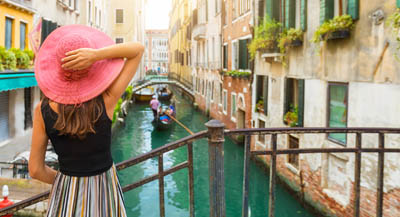 A woman watching gondolas from footbridge in Venice.