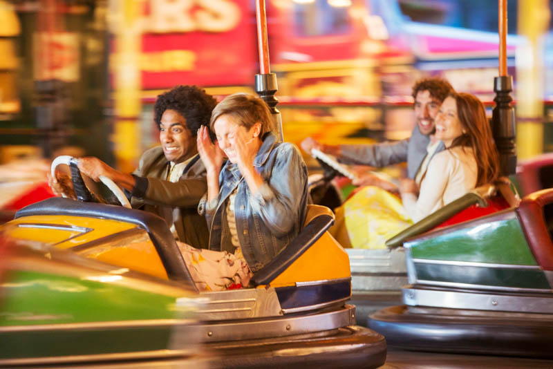 People playing in dodgem cars in a fairground.