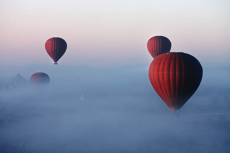 Hot air balloons rising throgh early morning cloud