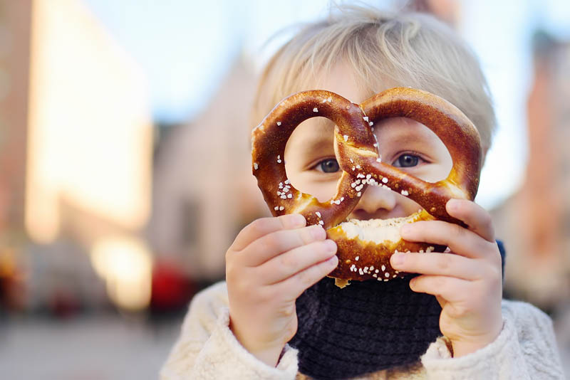 A small child looking through the holes in a soft pretzel