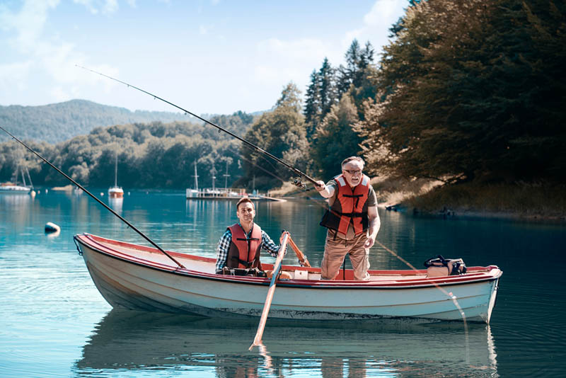 Two men fishing on a clear blue lake.