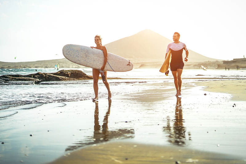 Two surfers carrying surf boards walking out into the surf.