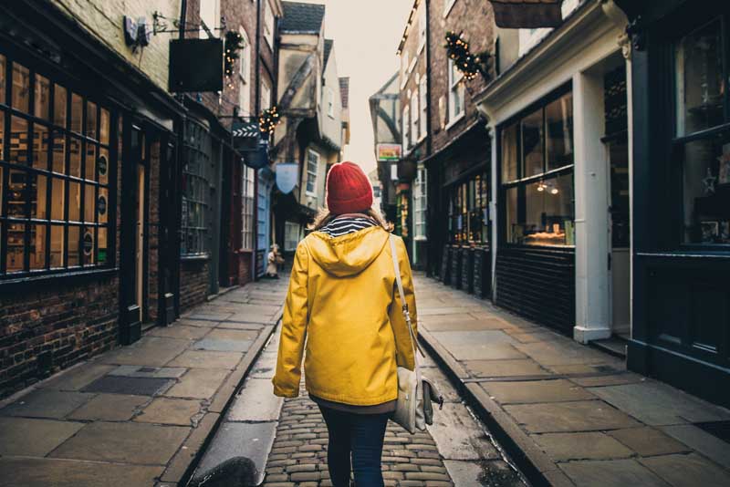 A woman walking down a stret in an old UK town.